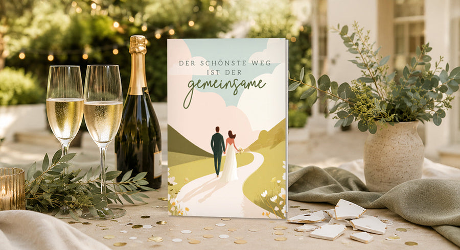 Wedding invitation on a table with champagne glasses and greenery.