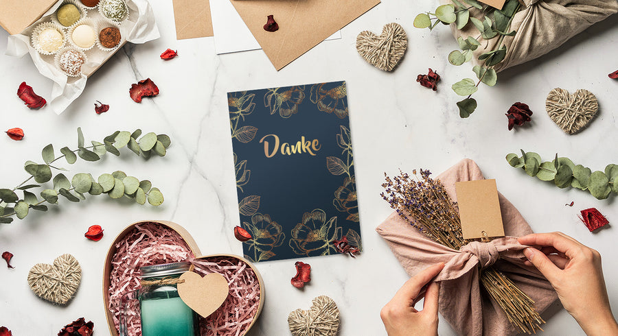 Gift wrapping supplies with a card and decorative elements on a table.